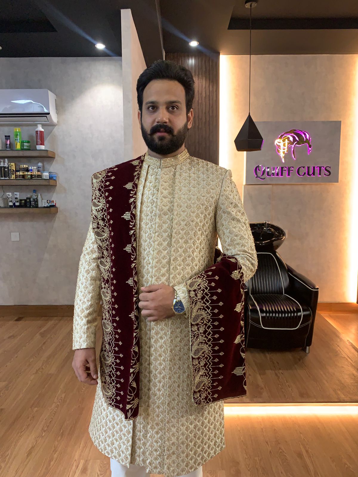 A groom in a gold sherwani and maroon shawl after his wedding grooming at Quiff Cuts, Faisalabad